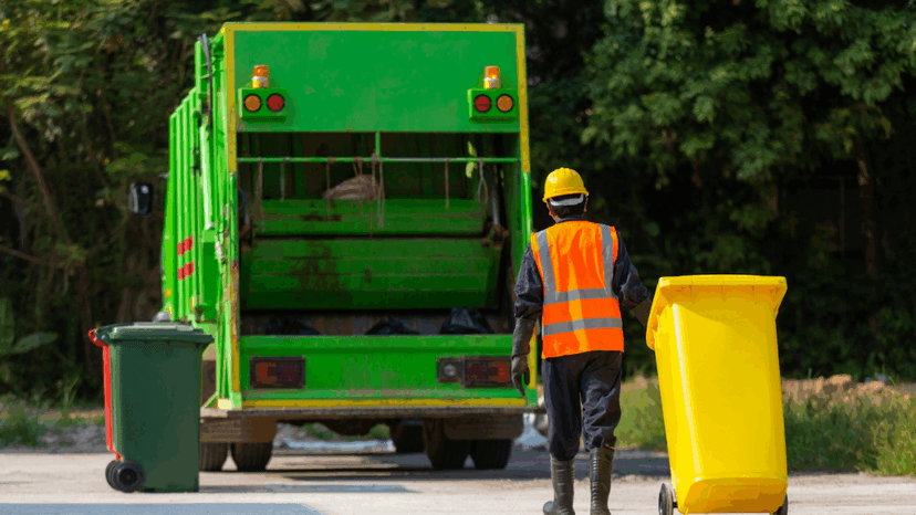 Garbage collector carries bin into the truck