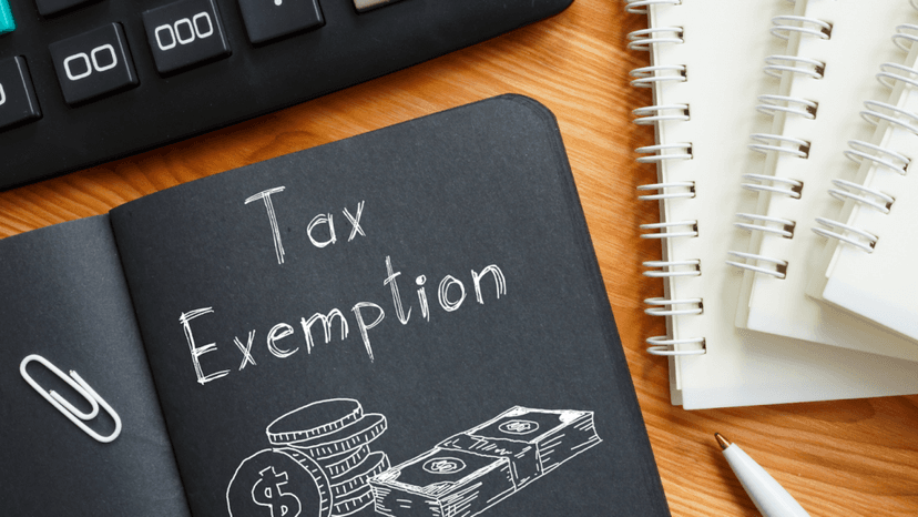 Handwritten Tax Exemption label in a black notebook beside a pen