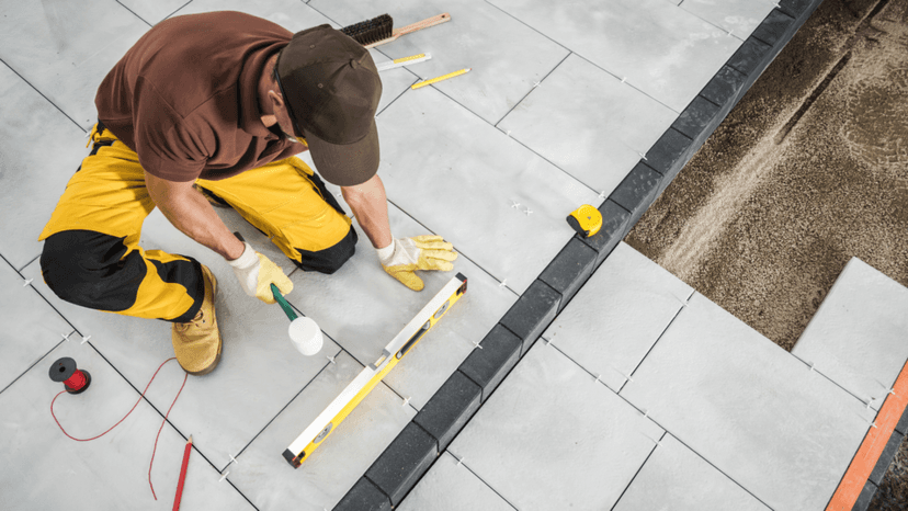 Worker laying patio tiles during basic home improvement project