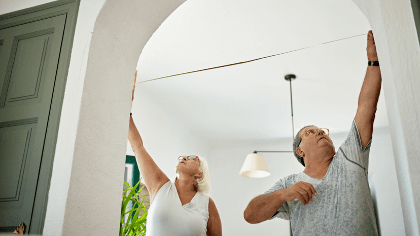 Homeowners measuring room dimensions for a property improvement