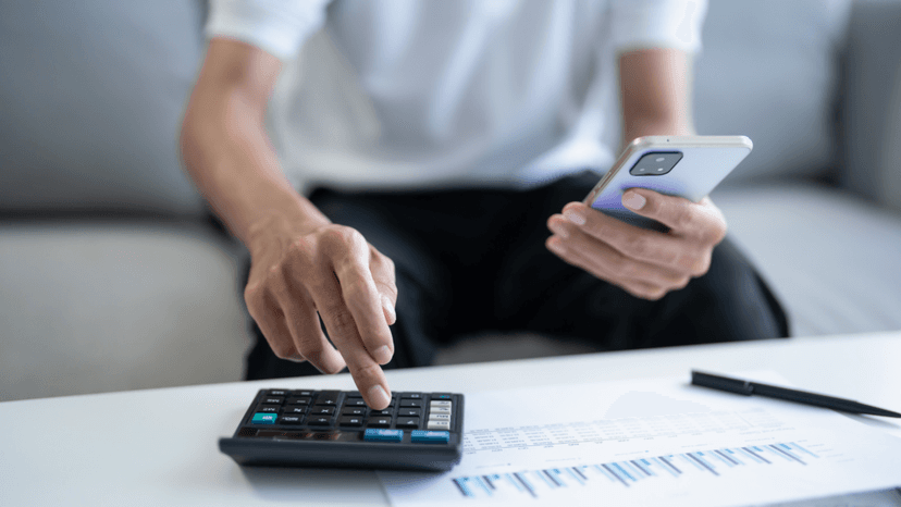Person using calculator and phone to review tax figures