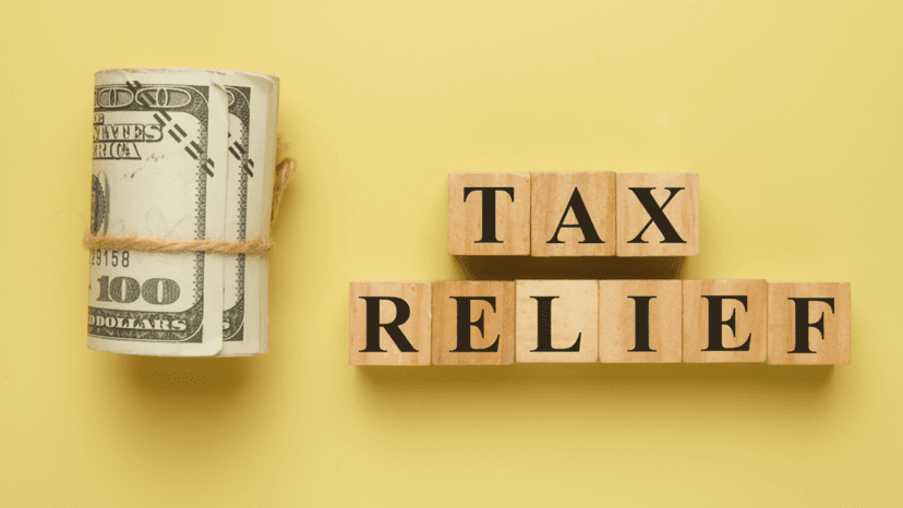 Tax relief savings concept with money and wooden letter blocks