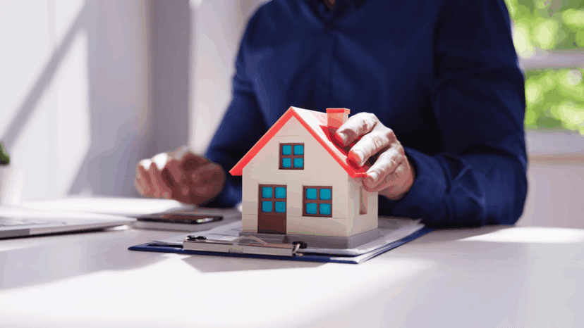 Person calculating real estate tax while holding mini house